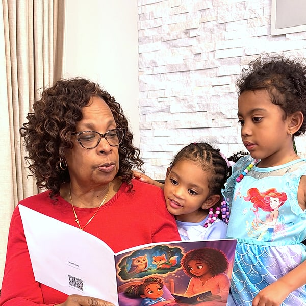 Two girls listening to a printed Mom Labs storybook being read aloud
